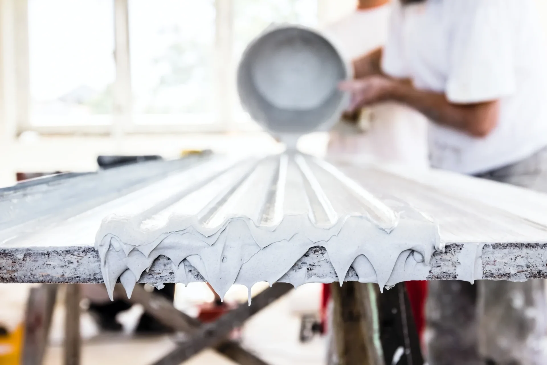 A person is pouring white paint on a table.